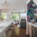 White kitchen and island with floral wallpaper in a nook