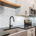 Gun Smoke painted kitchen cabinets with view of sink and tile backsplash