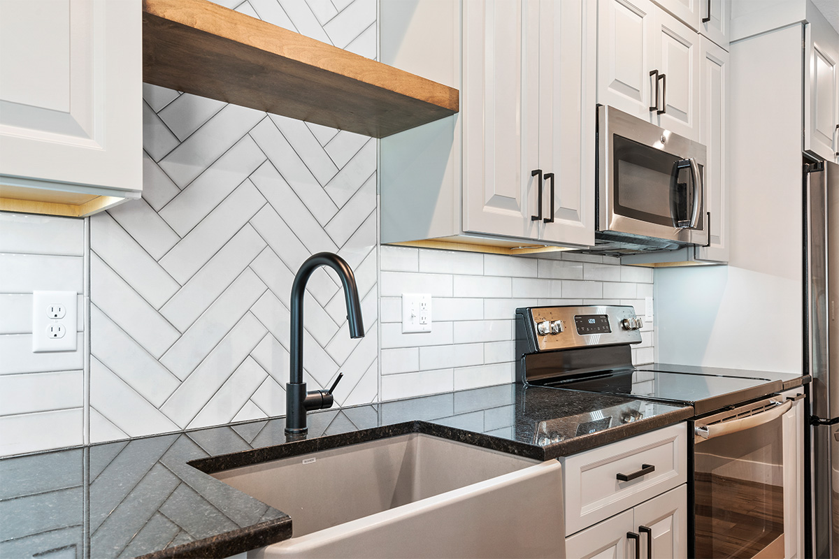 Gun Smoke painted kitchen cabinets with view of sink and tile backsplash
