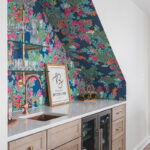 White kitchen and island with floral wallpaper in a nook