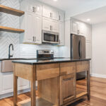 Painted Gun Smoke kitchen perimeter cabinets with a brown stained island cabinet.