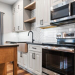 Painted Gun Smoke kitchen perimeter cabinets with a brown stained island cabinet.