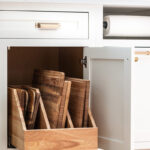 White painted kitchen cabinet with tray divider pullout drawer shown.