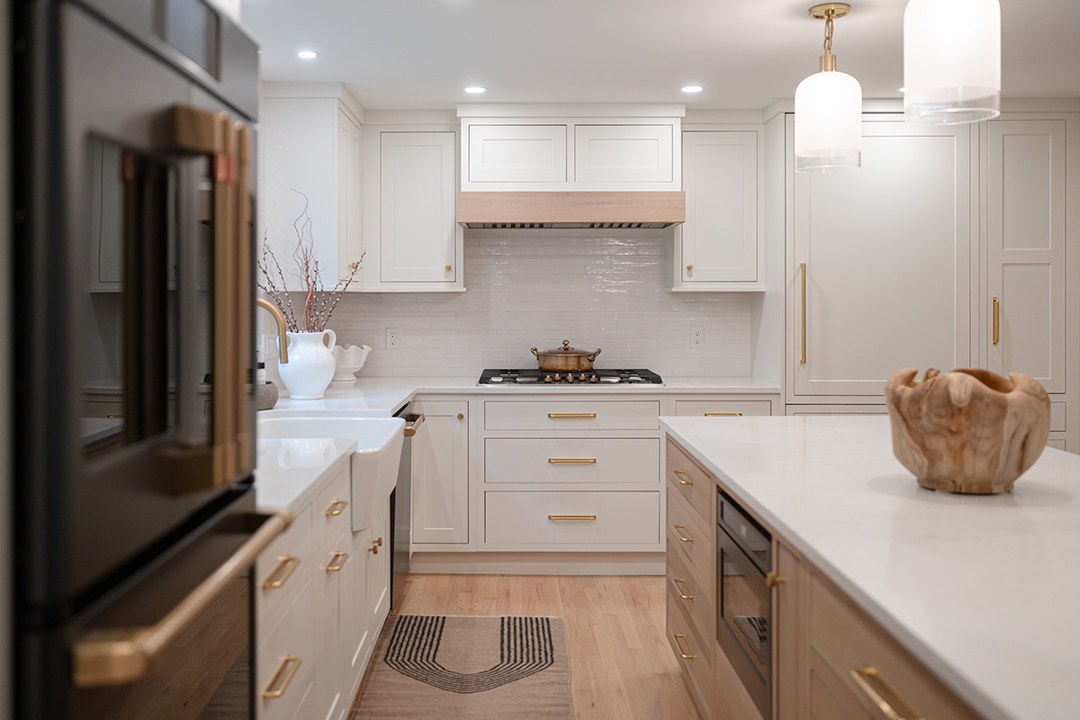Kitchen with White perimeter cabinets and Quartersawn White Oak island cabinets stained in light brown Pampas finish.