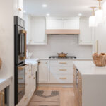 Kitchen with White perimeter cabinets and Quartersawn White Oak island cabinets stained in light brown Pampas finish.