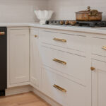 Kitchen with White perimeter cabinets and Quartersawn White Oak island cabinets stained in light brown Pampas finish.