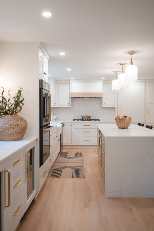 Kitchen with White perimeter cabinets and Quartersawn White Oak island cabinets stained in light brown Pampas finish.