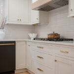 Kitchen with White perimeter cabinets and Quartersawn White Oak island cabinets stained in light brown Pampas finish.