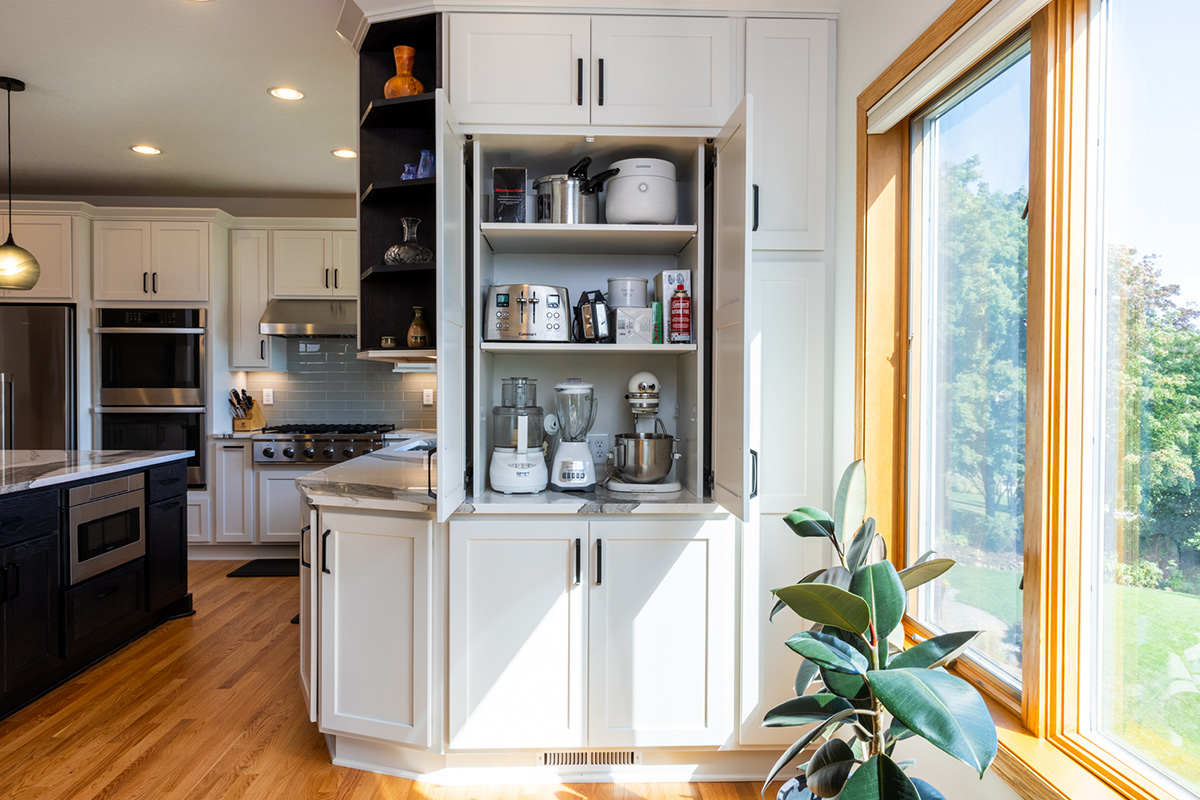 White kitchen storage cabinet that stores mixers and other appliances behind pocket doors