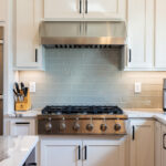 White kitchen cabinets. View of cooktop and hood above.