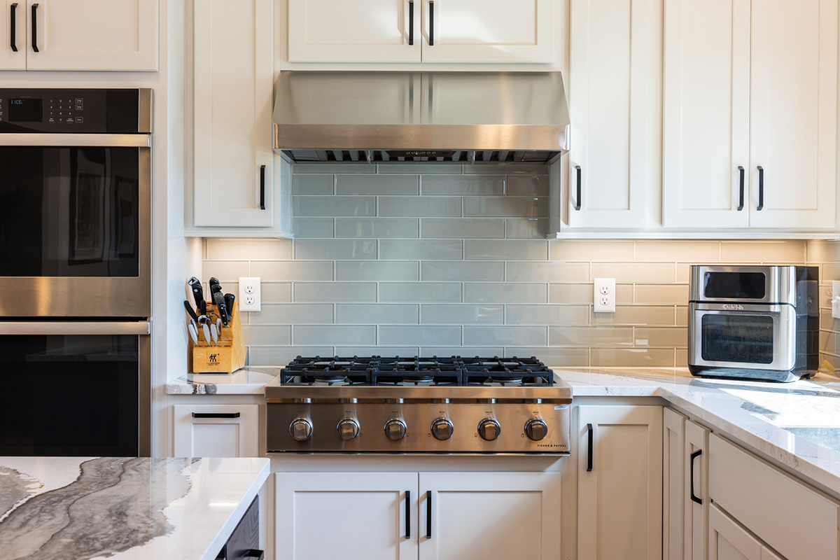 White kitchen cabinets. View of cooktop and hood above.