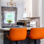 White and blue kitchen cabinets. Orange peninsula seats.