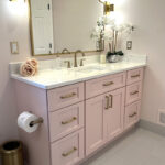 Pink bathroom with pink tile and single-sink vanity and gold rimmed mirror