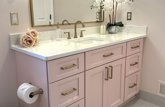 Pink bathroom with pink tile and single-sink vanity and gold rimmed mirror