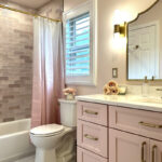 Pink bathroom with pink tile and single-sink vanity and gold rimmed mirror