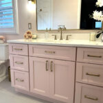 Pink bathroom with pink tile and single-sink vanity and gold rimmed mirror