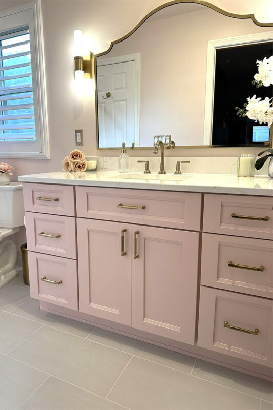 Pink bathroom with pink tile and single-sink vanity and gold rimmed mirror
