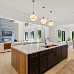 Dark stained kitchen island looking towards an open layout living room with large white sofa and a contemporary fireplace.