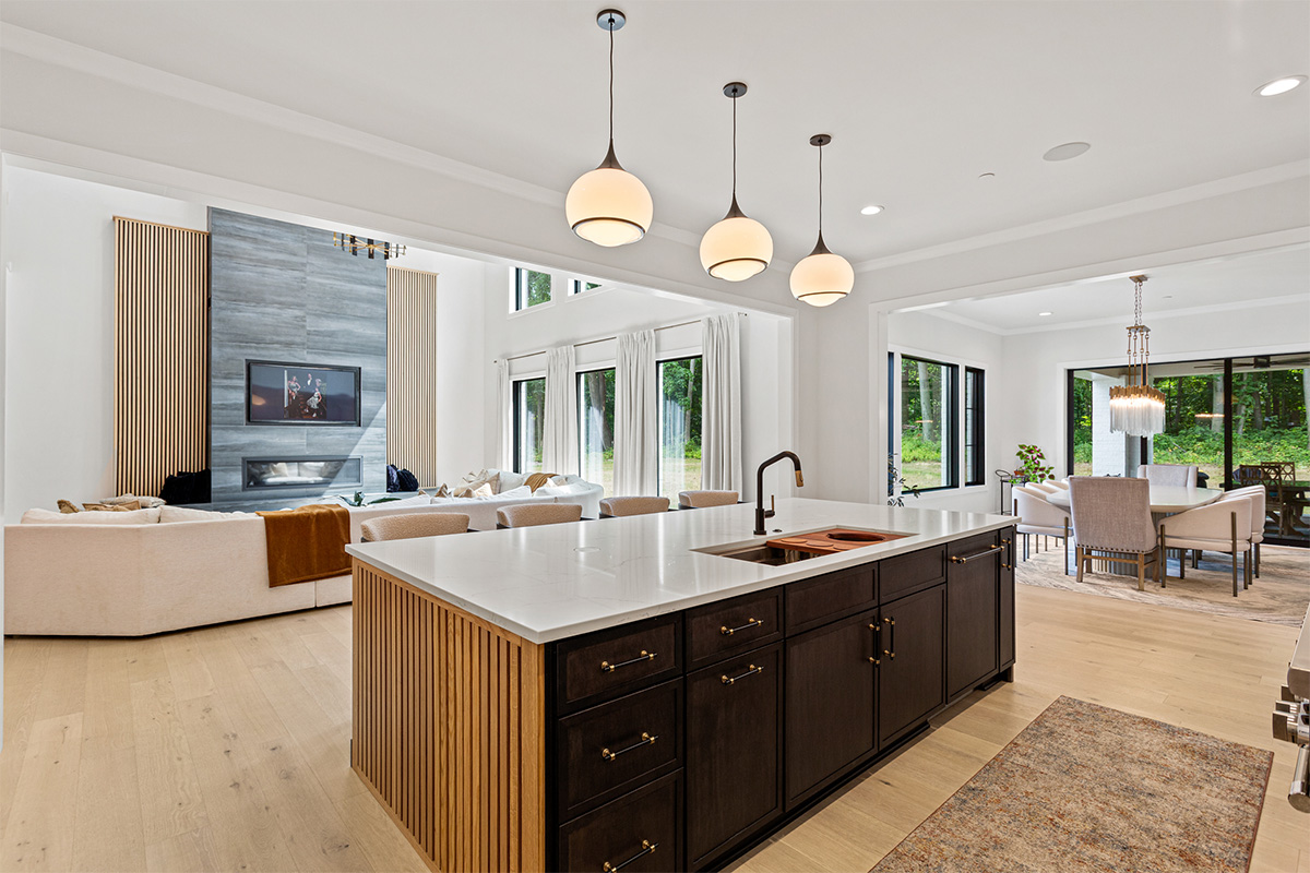 Dark stained kitchen island looking towards an open layout living room with large white sofa and a contemporary fireplace.