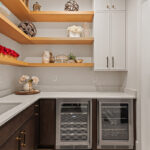 Prep kitchen with dark stained and white painted cabinets and natural floating shelves