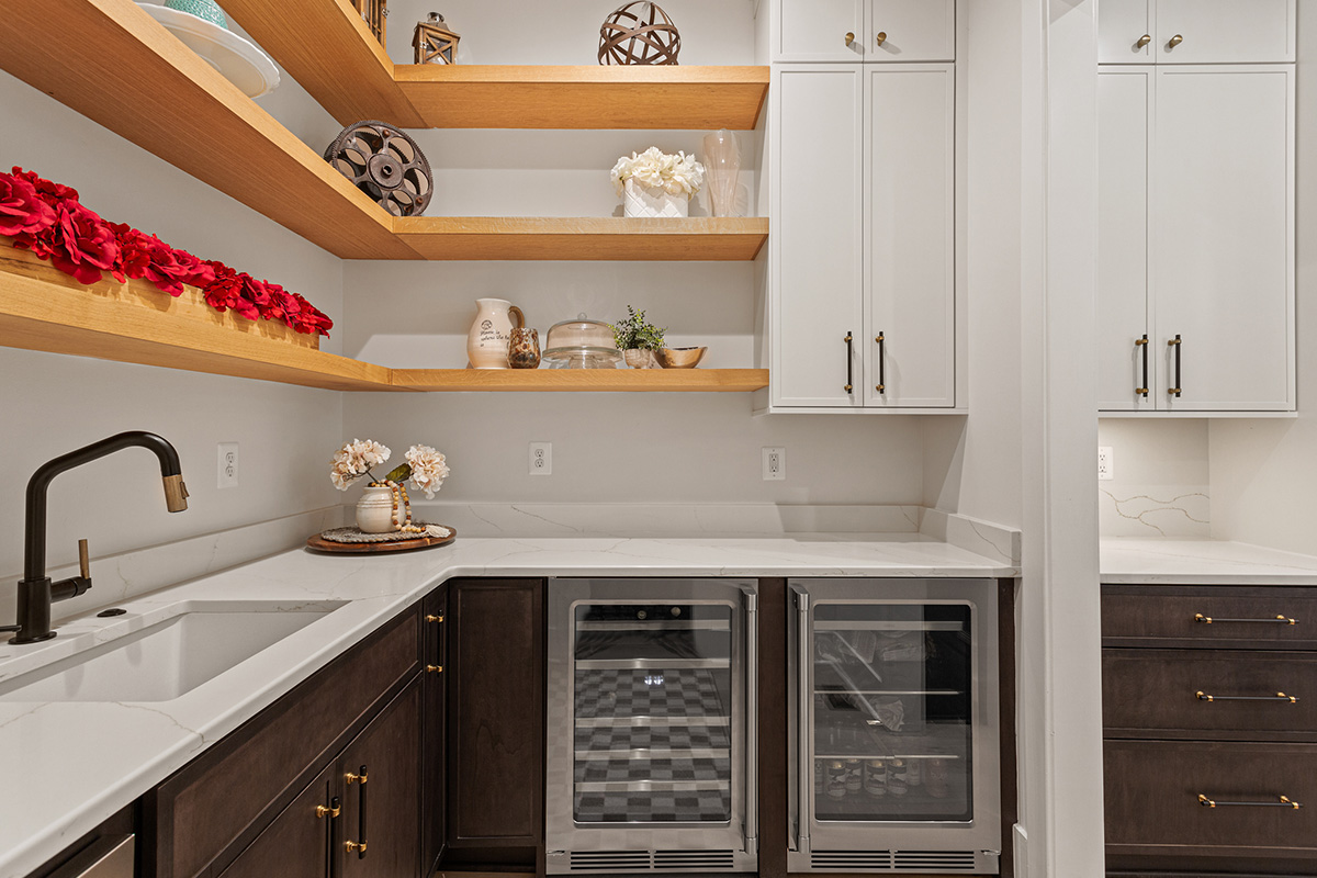 Prep kitchen with dark stained and white painted cabinets and natural floating shelves