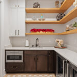 Prep kitchen with dark stained and white painted cabinets and natural floating shelves