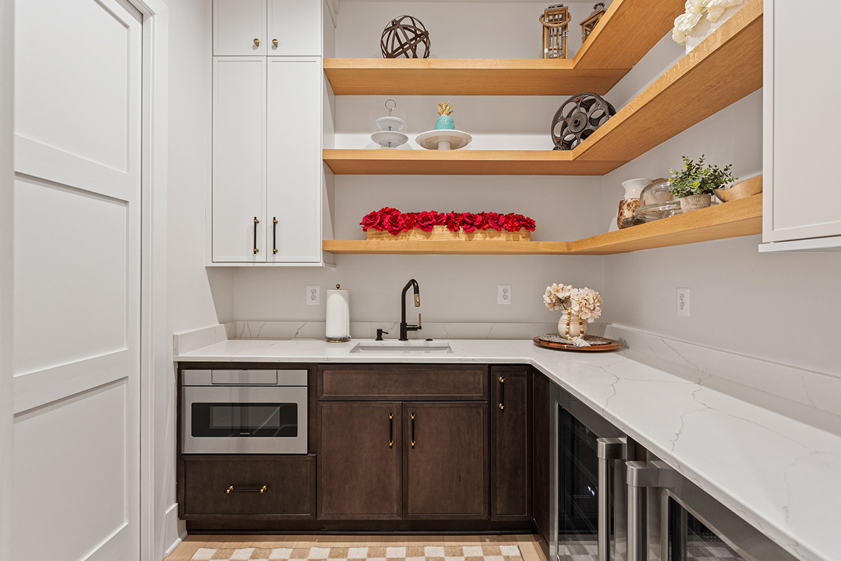 Prep kitchen with dark stained and white painted cabinets and natural floating shelves