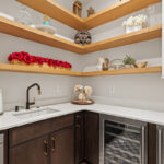 Prep kitchen with dark stained cabinets and natural floating shelves