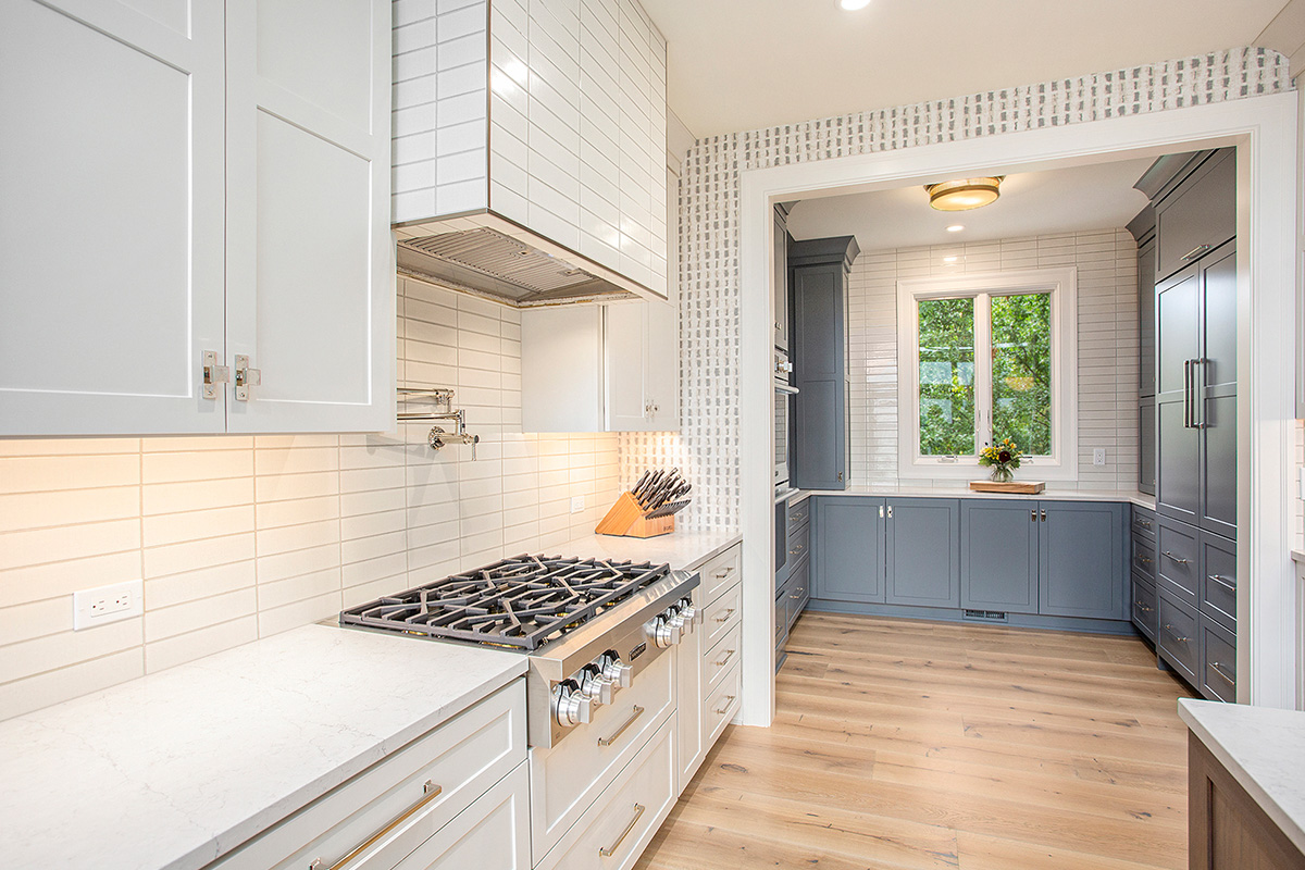 White kitchen cabinets with a view towards a blue painted pantry