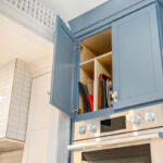 Blue painted cabinet above oven with tray storage