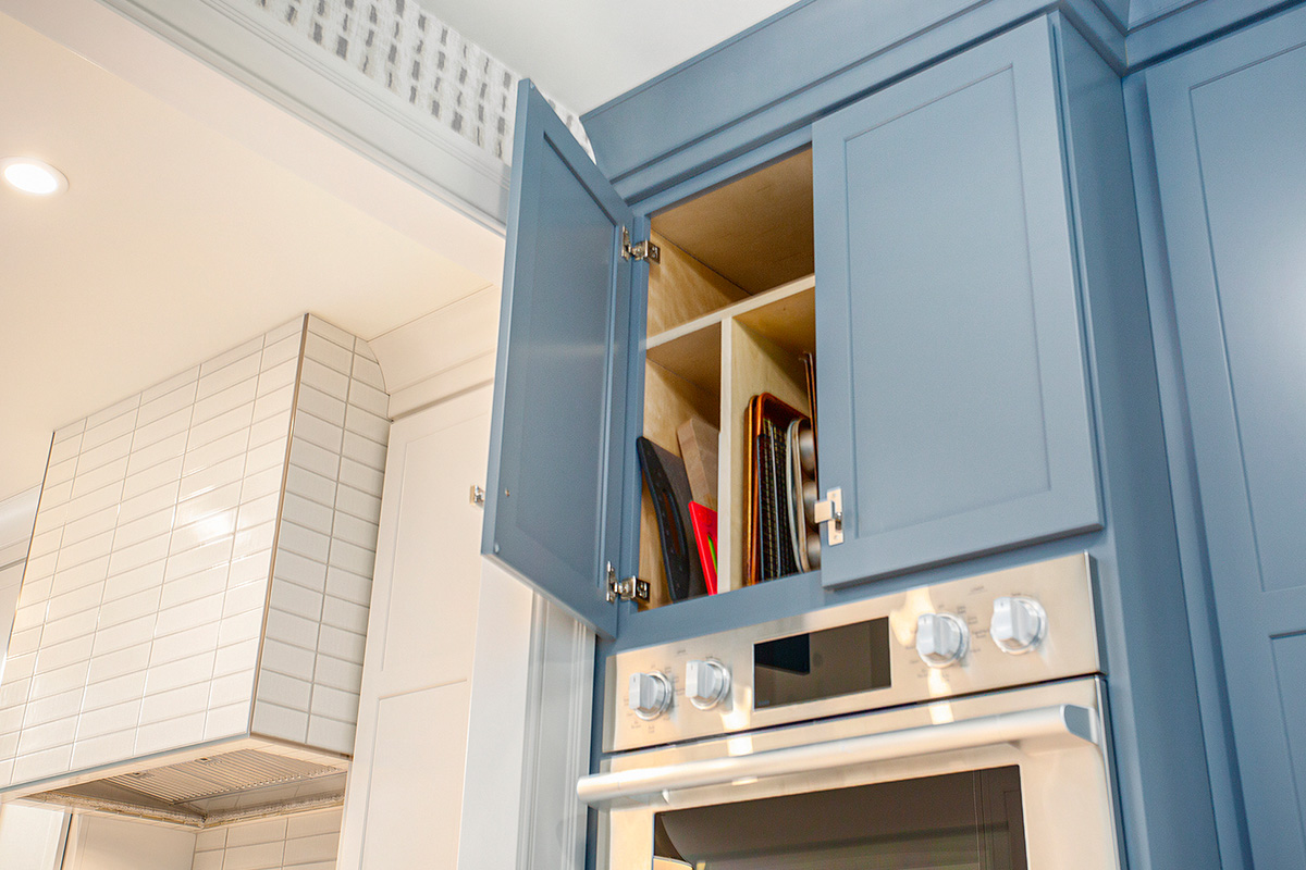 Blue painted cabinet above oven with tray storage