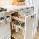 White kitchen cabinet with pull-out utensil storage beside the cook top range