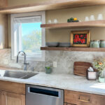 Cashew-stained floating shelves above cabinets, dishwasher and sink