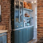 Purple painted bar cabinets with wine bottles and open shelves.