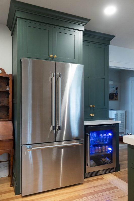 Purple painted kitchen cabinets with stainless steel fridge and beverage cooler.