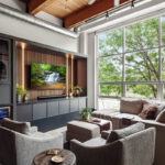 Contemporary entertainment center with gray painted cabinets and stained slatted back wall behind a large mounted tv.