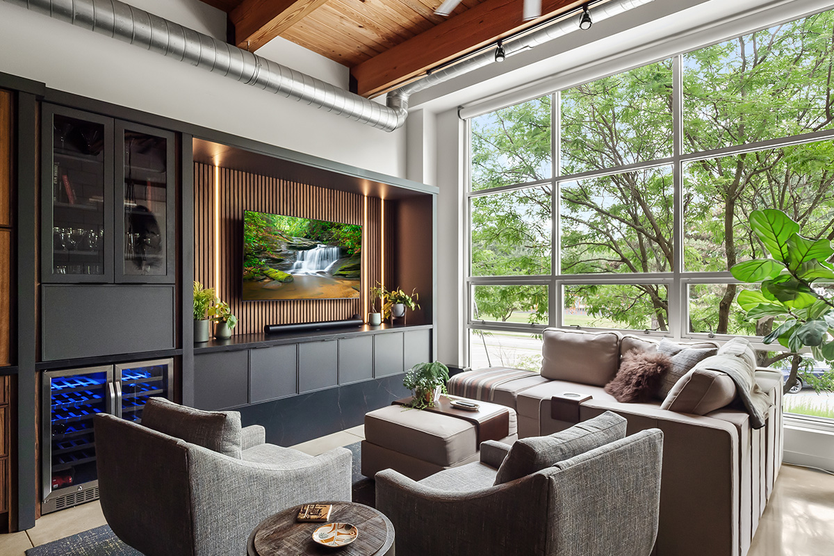 Contemporary entertainment center with gray painted cabinets and stained slatted back wall behind a large mounted tv.