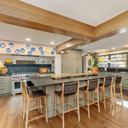 Brown painted kitchen with island and wood beams.