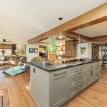 Brown painted kitchen with island and wood beams.