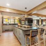 Brown painted kitchen with island and wood beams.