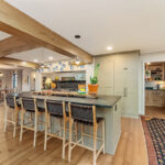 Brown painted kitchen with island and wood beams.