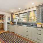 Brown painted kitchen with island and wood beams.