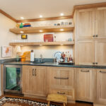 Bar with light brown stained cabinets and floating shelves.