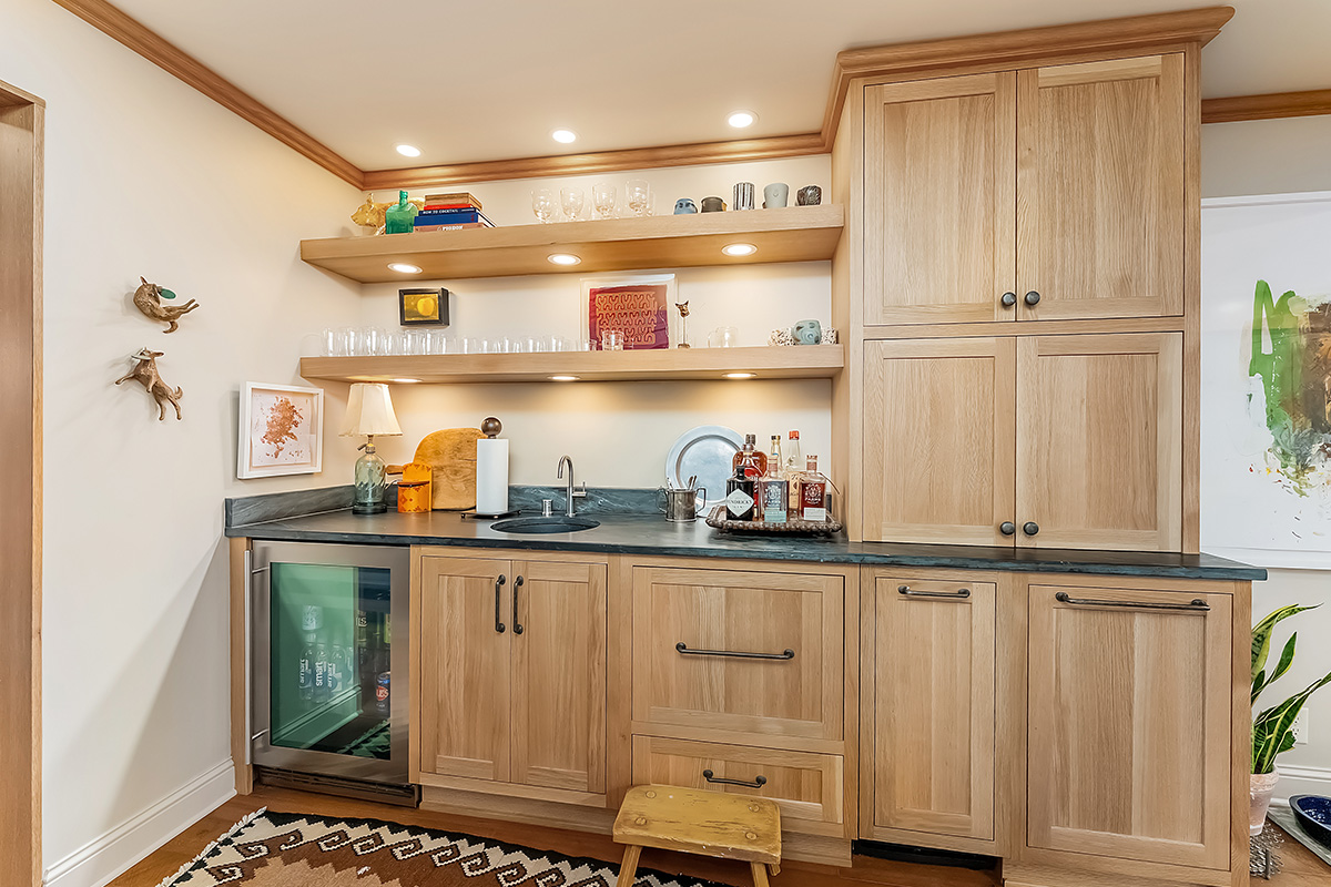 Bar with light brown stained cabinets and floating shelves.