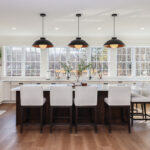 White perimeter kitchen cabinets with a dark stained island.