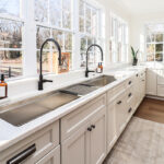 White kitchen cabinets with large row of windows above.