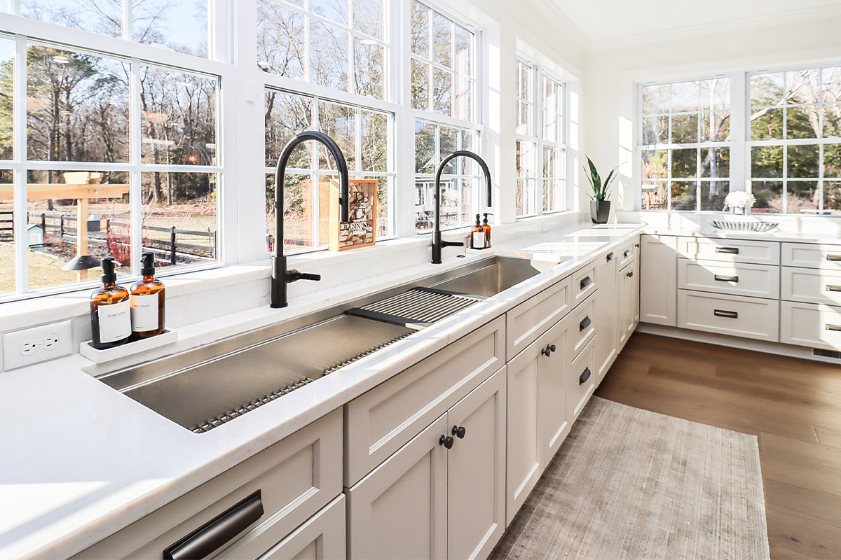 White kitchen cabinets with large row of windows above.
