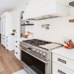 White kitchen cabinets with large hood.