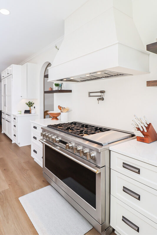 White kitchen cabinets with large hood.