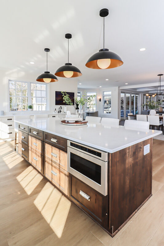 White perimeter kitchen cabinets with a dark stained island.